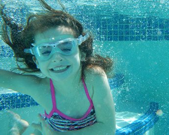 young girl swimming underwater with goggles 
