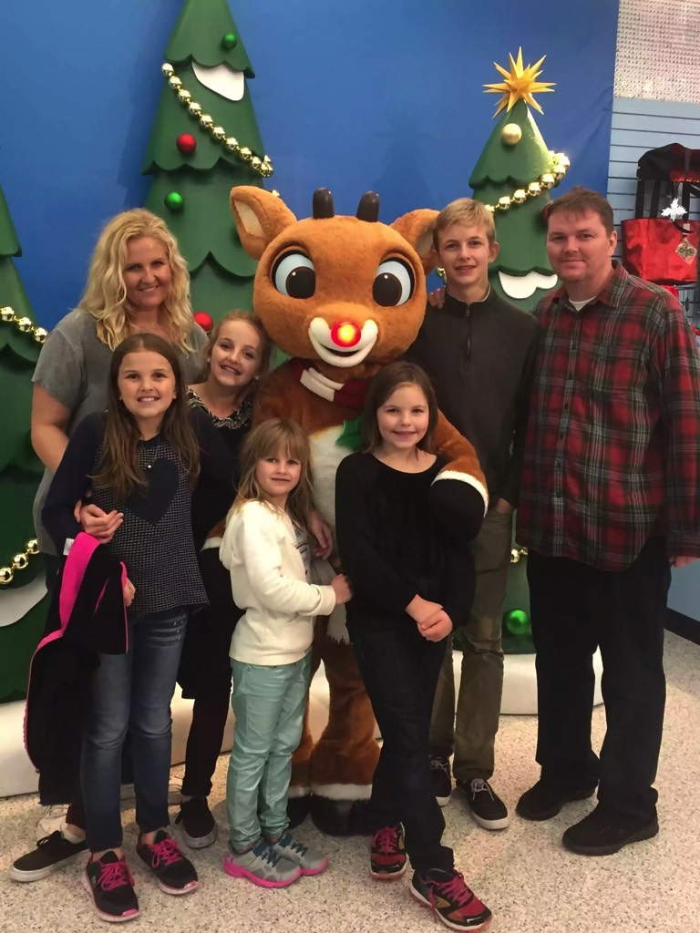 family posing with Rudolph the Reindeer character during a JAJF WOW experience 