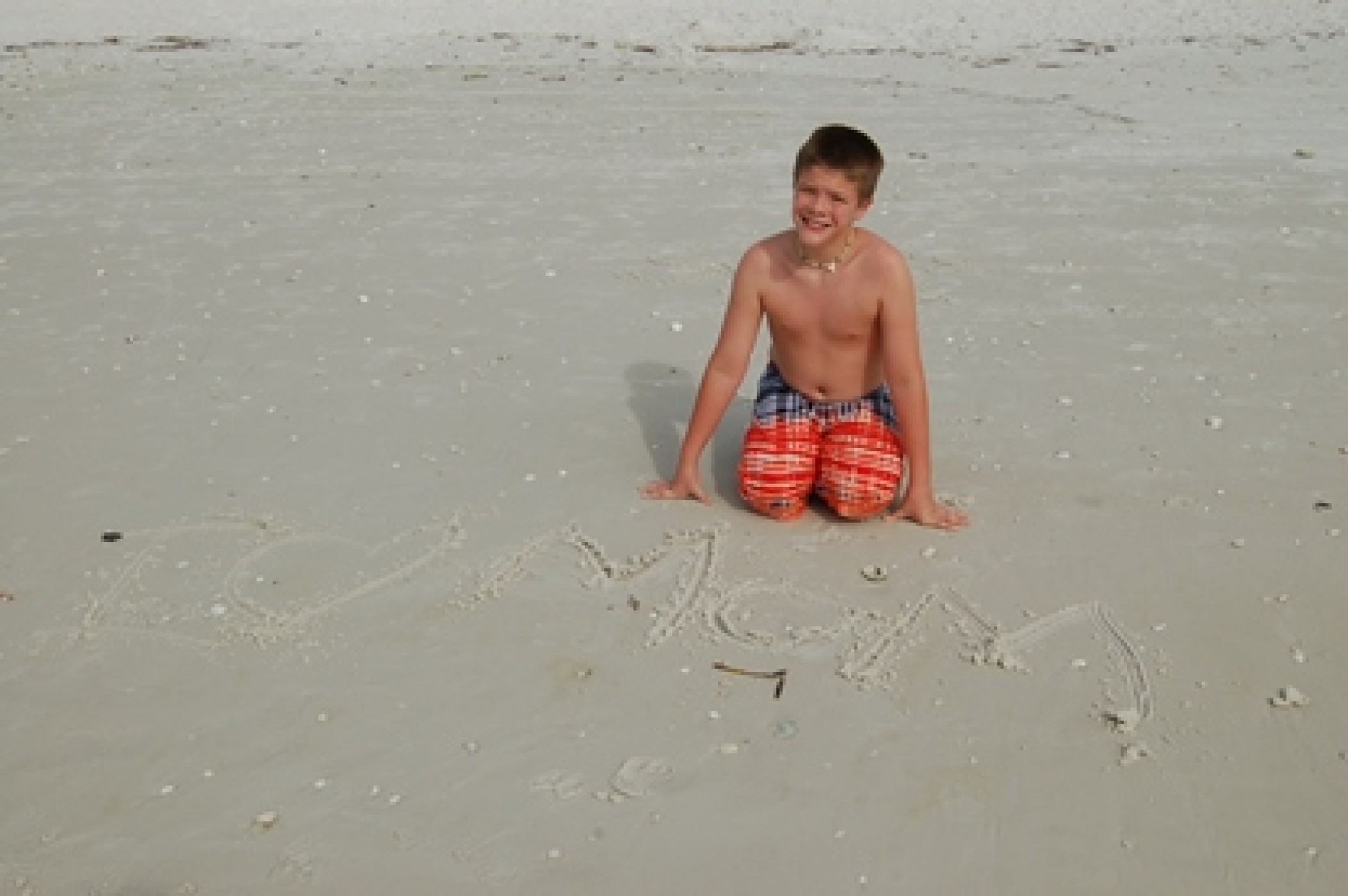 young boy on beach with I Love Mom caved into the sand during a JAJF WOW experience 