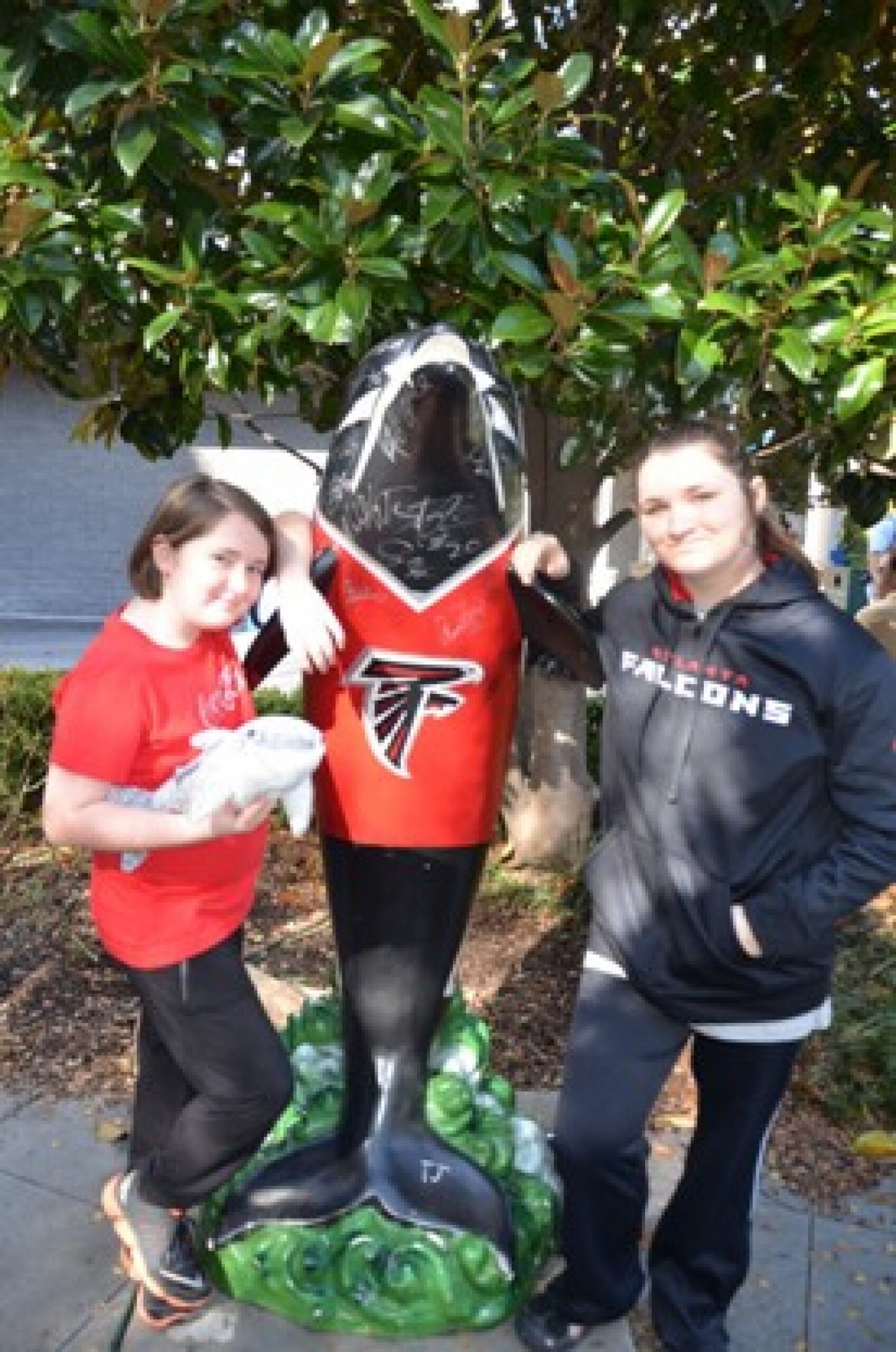 two girls at Atlanta Falcons statue during a JAJF WOW experience 