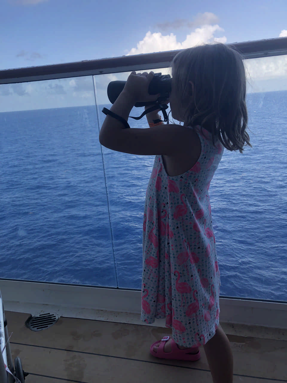 little girl looking across ocean with binoculars enjoying a JAJF late stage cancer timeout 