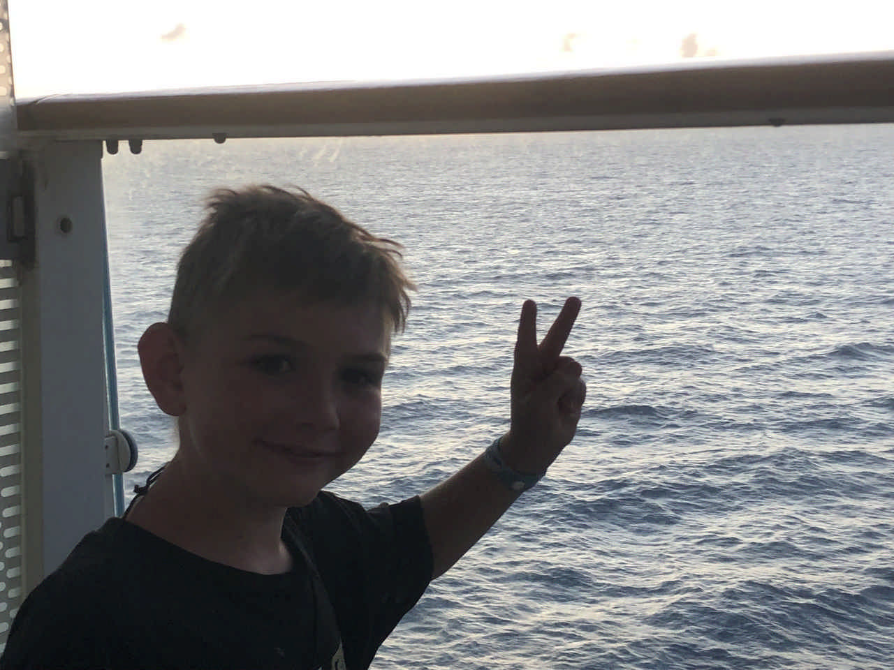 young boy on ferry boat holding his fingers in a peace sign during a JAJF late stage cancer timeout 