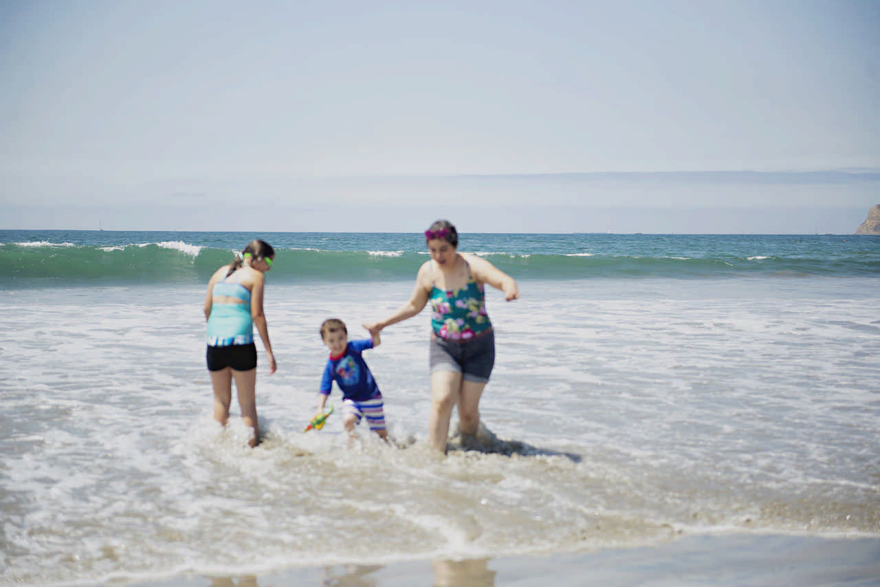 mom and children playing in the ocean during a JAJF late stage cancer timeout 