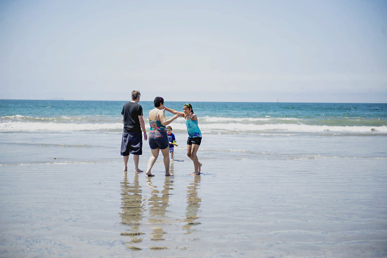 family walking on the beach through the water on a JAJF cancer timeout 