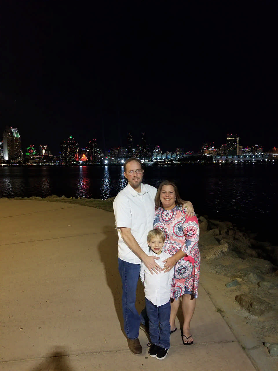 dad and mom with their son posing at night in front of city skyline during JAJF timeout 