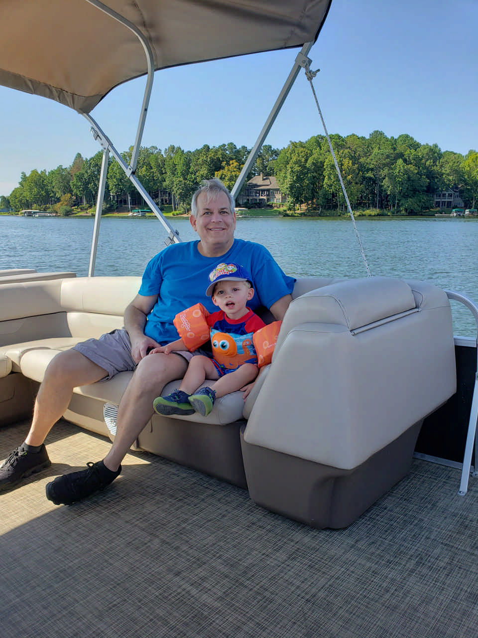 man sitting with toddler boy on pontoon boat during a JAJF WOW experience 