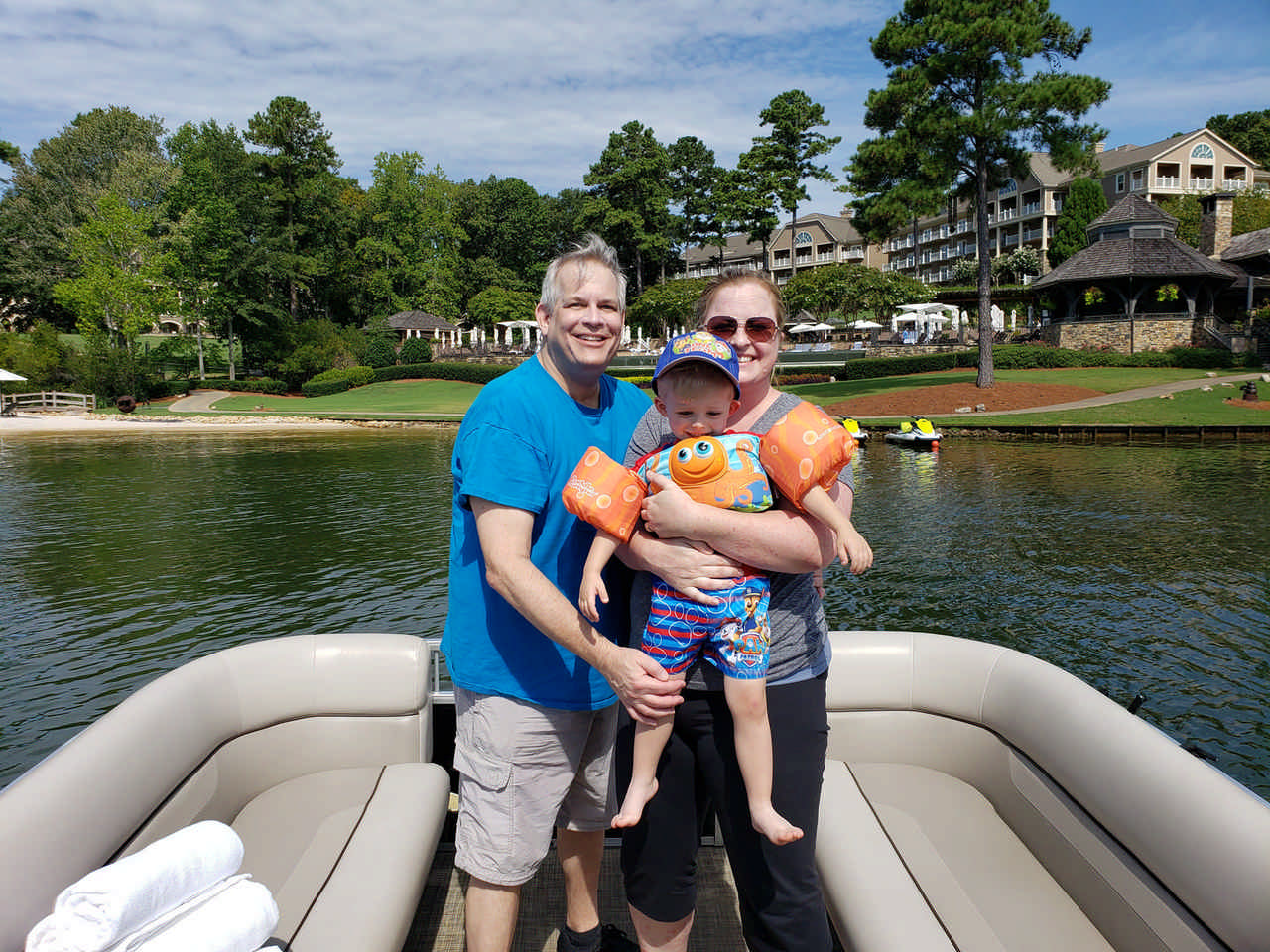 couple holding toddler boy on pontoon boat during a JAJF WOW experience 