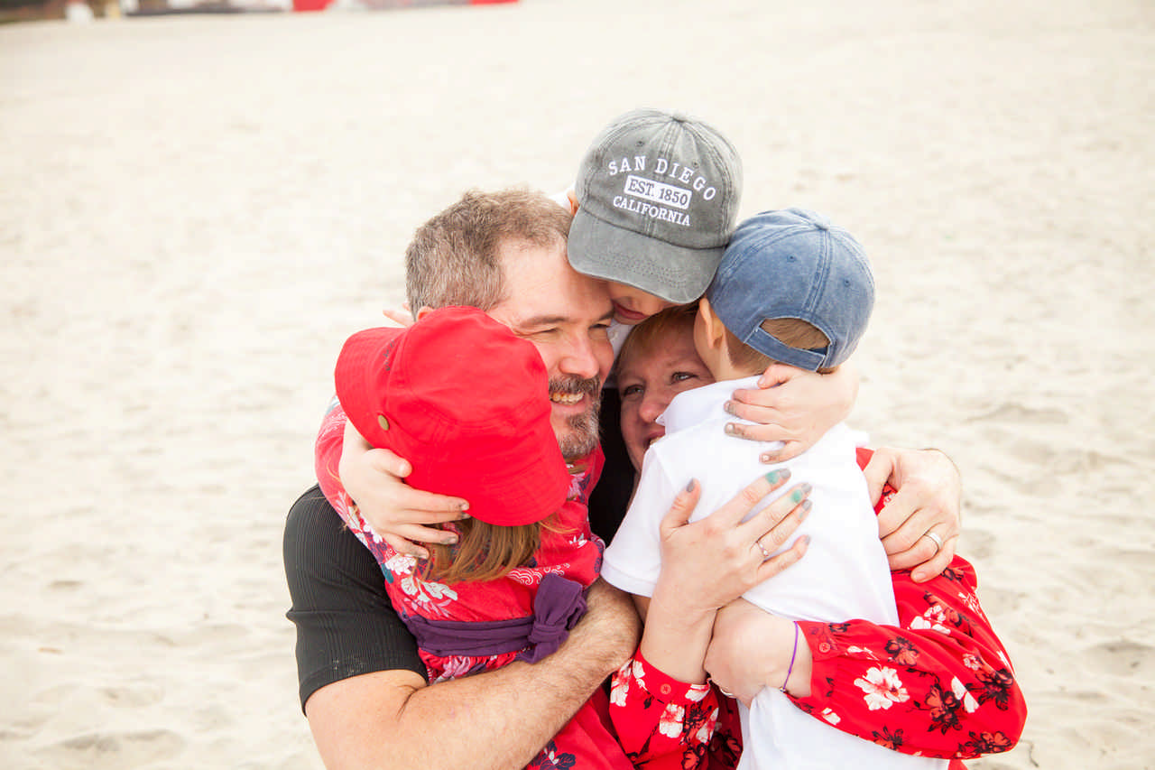 family hugging in the sand on the beach during a Jack and Jill Foundation WOW experience 