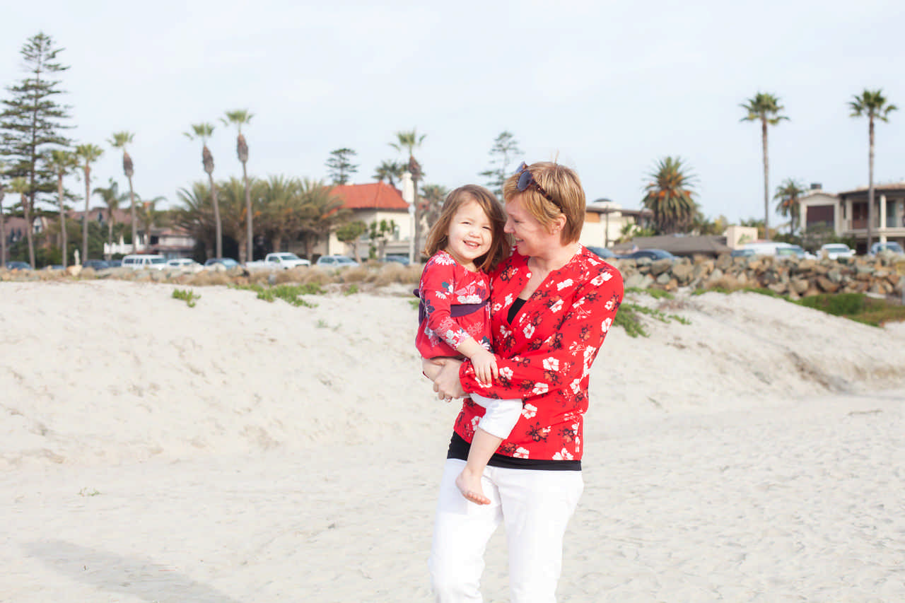 mom holding her toddler daughter on the beach during a Jack and Jill Foundation WOW experience 