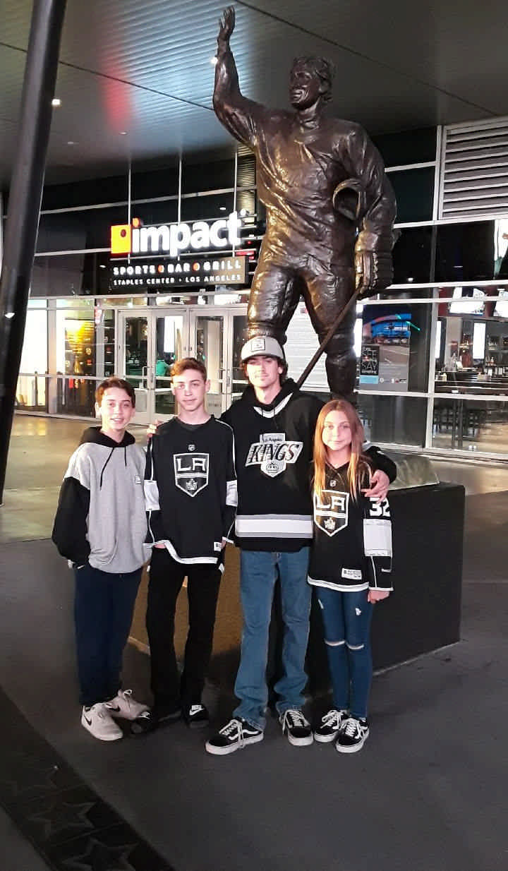 family posing with LA King hockey statue on a JAJF WOW experience 