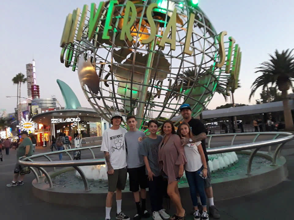 family posing in front of Universal Studios globe on a JAJF WOW experience 