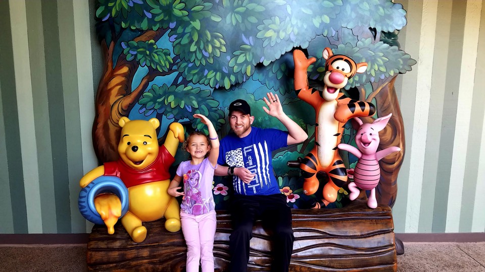 dad and daughter posing with Winnie the Pooh statues enjoying The Power of WOW experience 