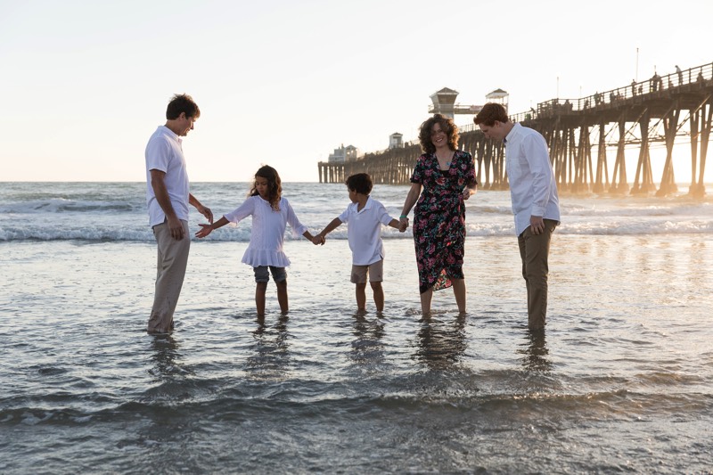 family wearing white shirts and khakis on the beach during sunset enjoying a JAJF WOW experience 