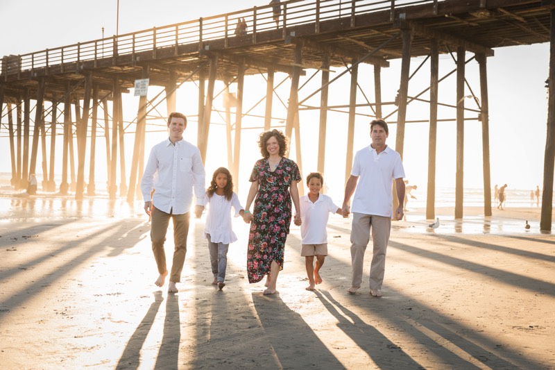 family with white shirts and khakis on beach by boardwalk enjoying a JAJF WOW experience 