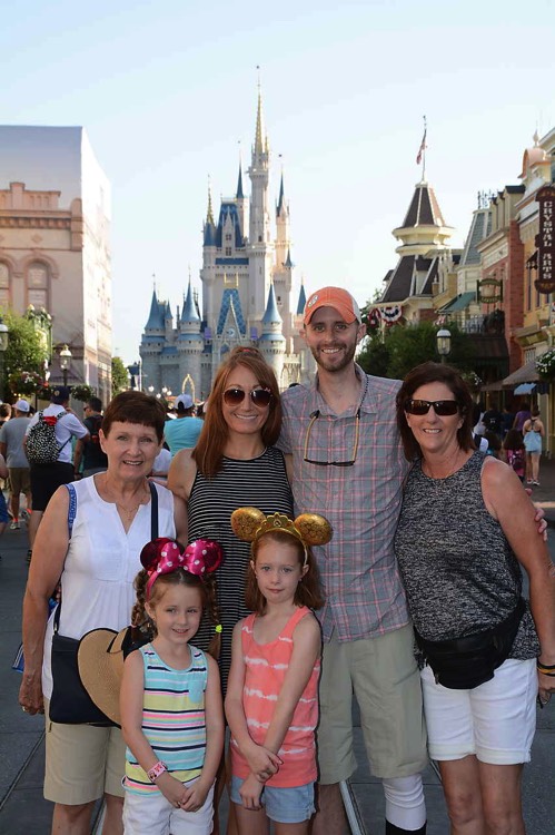 family with two young daughters wearing Minnie ears in front of Cinderella's castle during a JAJF trip treating the families not the cancer 