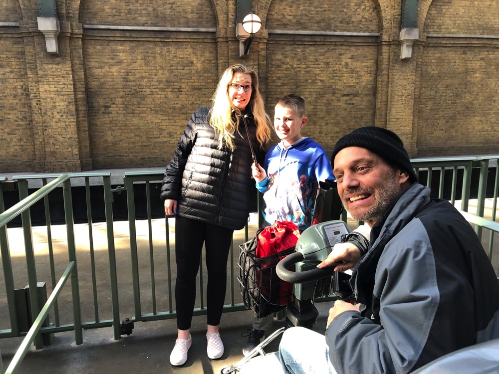 mom and dad with son waiting for Hogwarts train on a JAJF WOW experience 