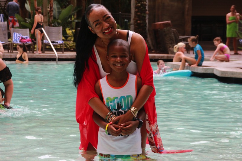 mom hugging son from behind at swimming pool enjoying a JAJF Wow Experience 