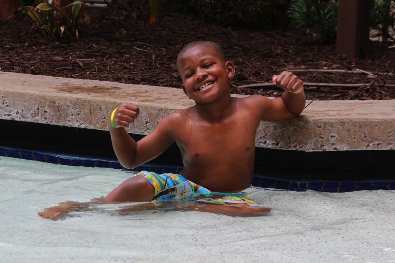 young boy flexing his muscles in the pool enjoying a JAJF Wow Experience 