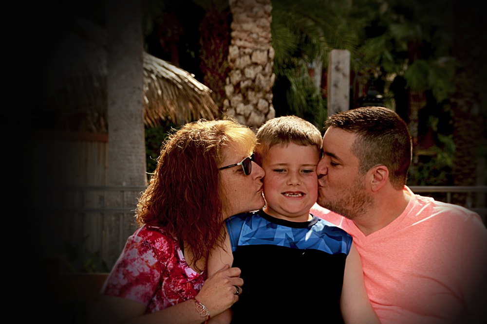 mom and dad kissing sons cheek on a JAJF WOW experience 