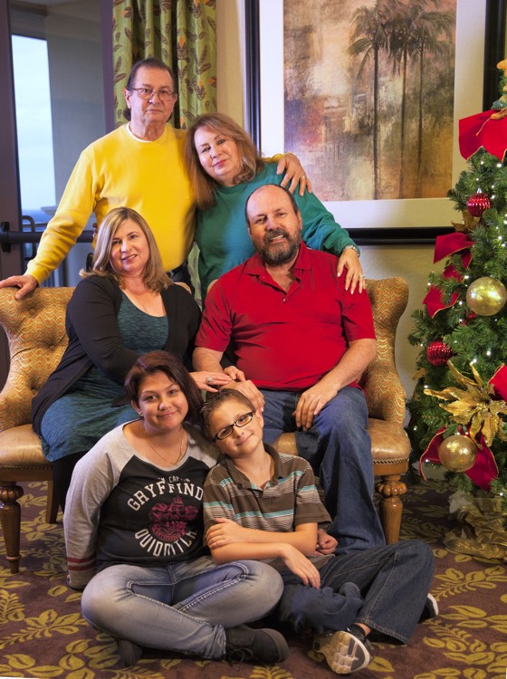 family sitting on couch beside Christmas tree during a JAJF trip treating the families not the cancer 
