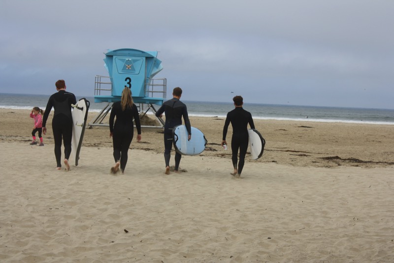 family in wetsuits with surfboards walking to the beach enjoying a JAJF Wow Experience 