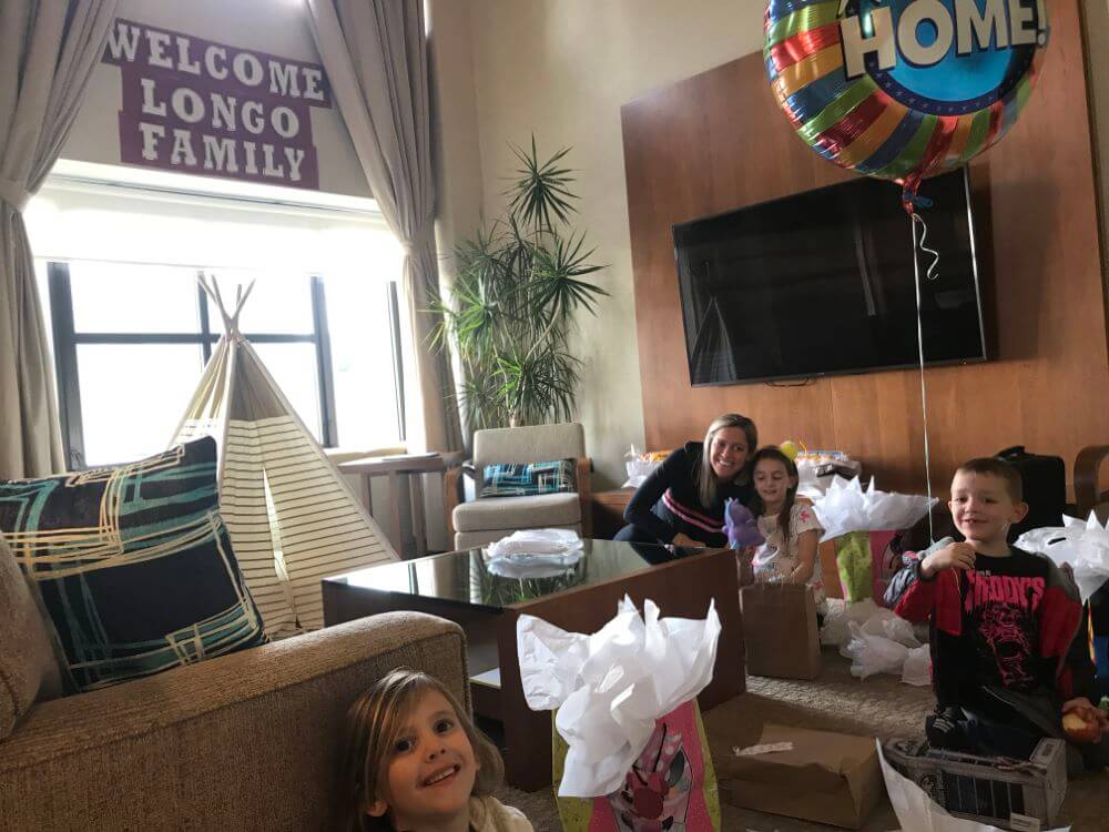 family in hotel room with welcome banner enjoying The Power of WOW experience 
