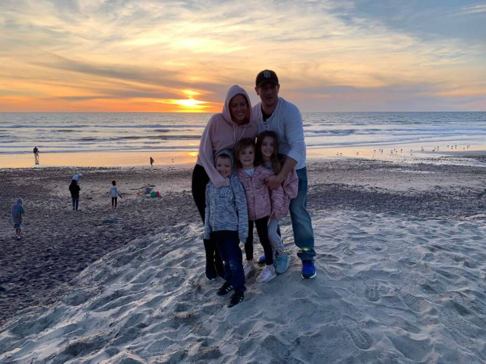 couple with three kids on the beach at sunset enjoying The Power of WOW experience 