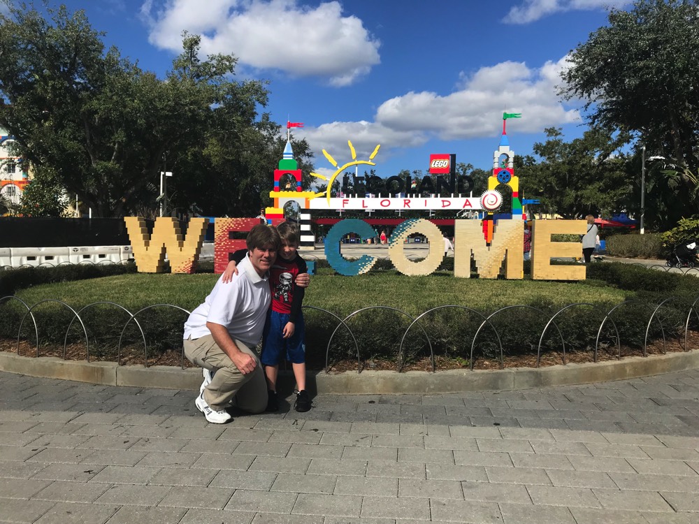 dad and son at Legoland Welcome sign on a JAJF WOW experience 
