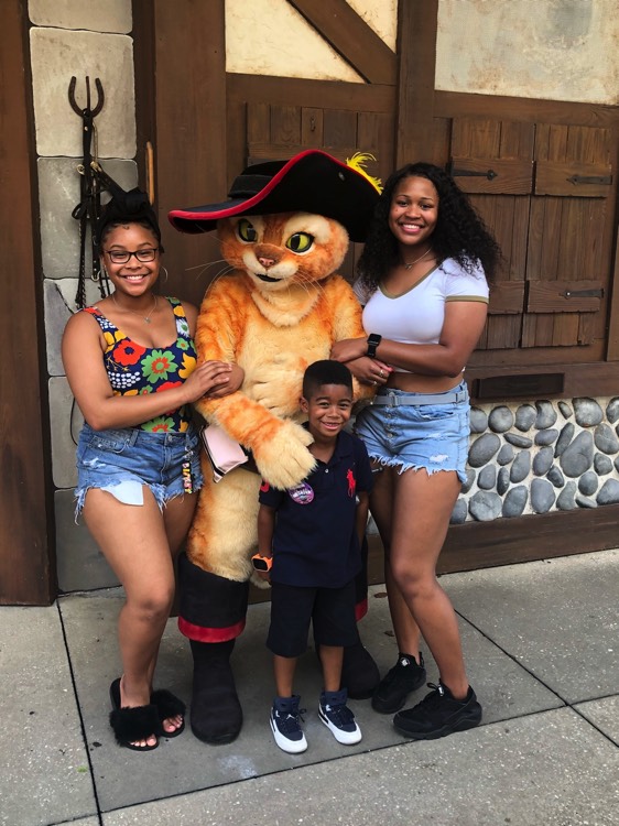 sisters and brother posing with Puss in Boots character on a JAJF WOW experience 