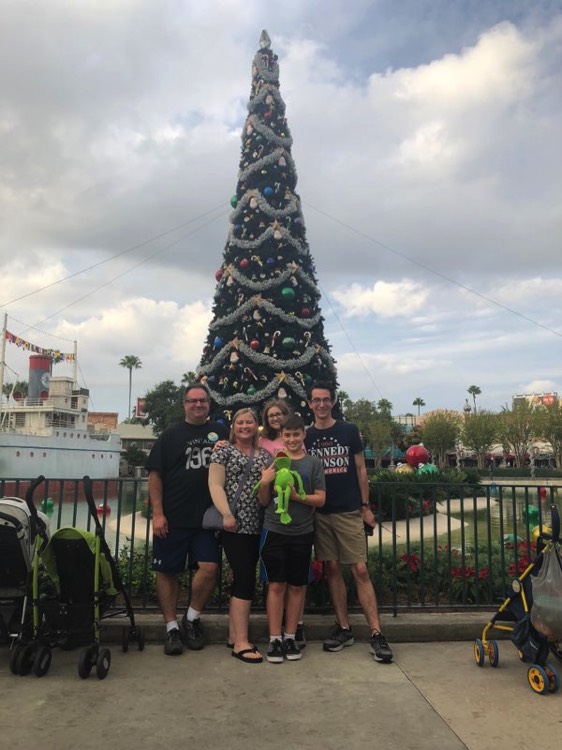 family in front of Christmas tree at Disney World on a JAJF WOW experience 