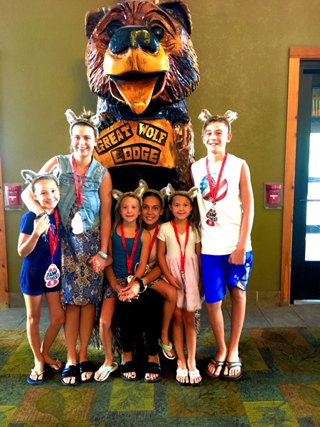 family wearing wolf ear headbands beside Great Wolf Lodge statue enjoying a JAJF WOW experience 