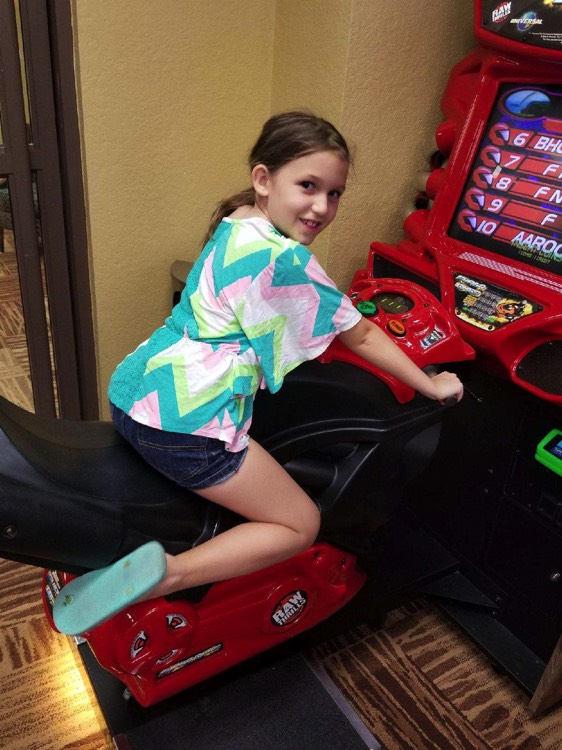 young girl on motorcycle arcade game during a JAJF trip treating the families not the cancer 