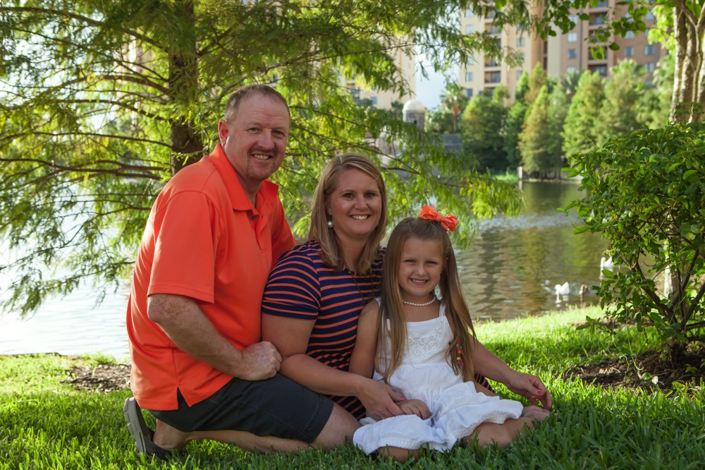 mom and dad posing with daughter by lake on a JAJF WOW experience 